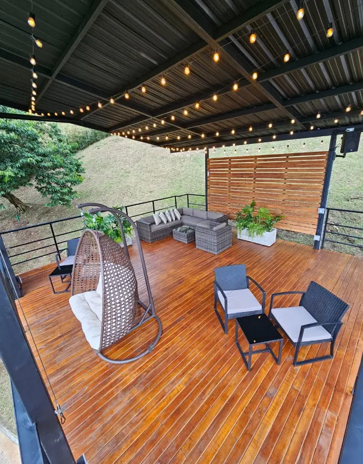 Terraza social de madera con mobiliario y luces cálidas
